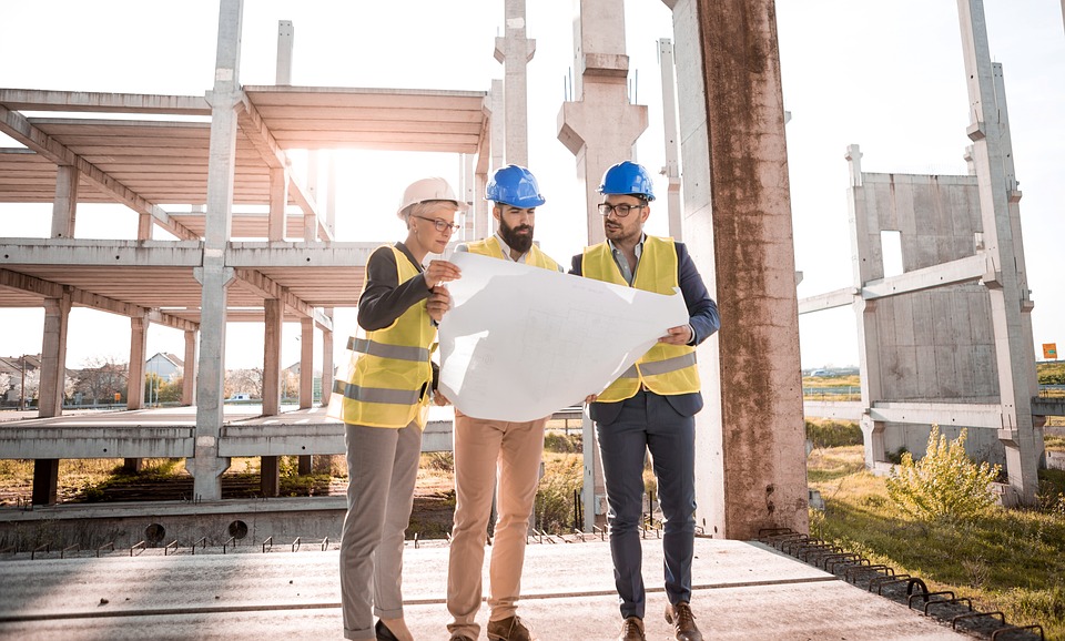 Builders in hard hats reviewing plans on a construction site